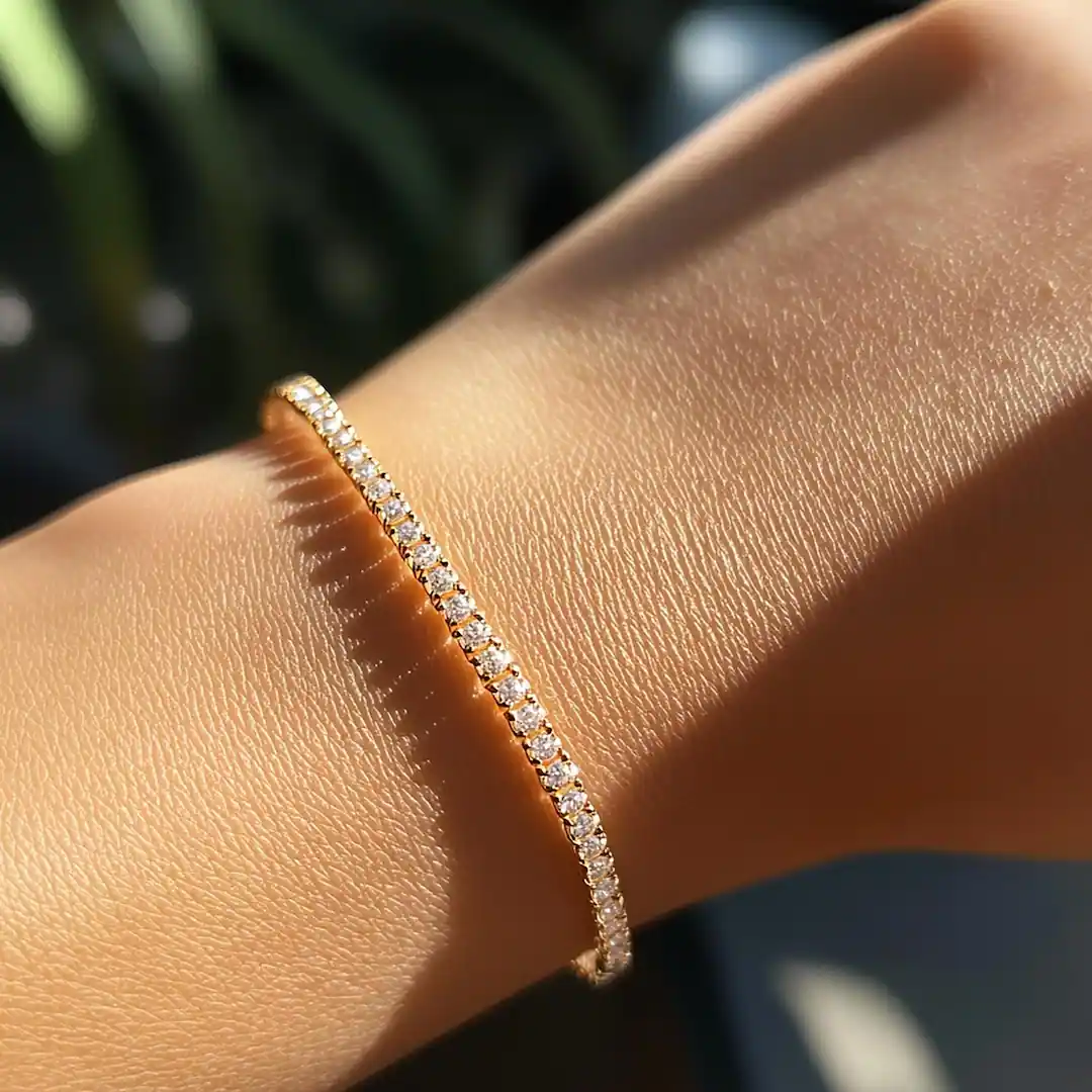 A diamond tennis bracelet in gold worn on the wrist, catching the sunlight