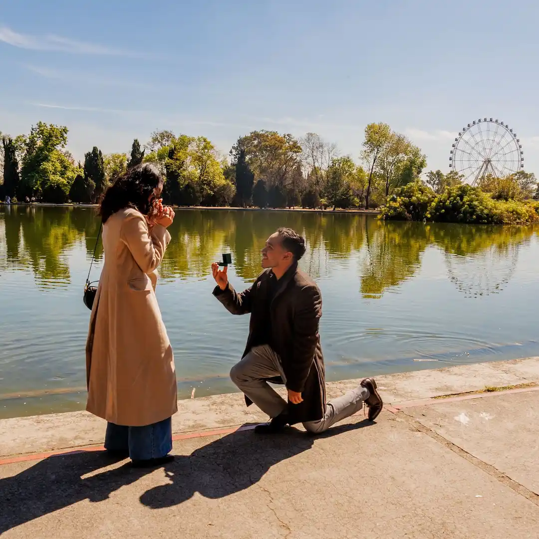 A lakeside marriage proposal, a man on one knee presenting the engagement ring box